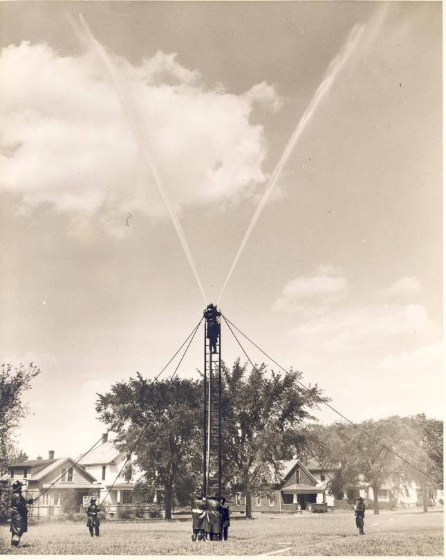 Firemen practice the church raise with a ladder.